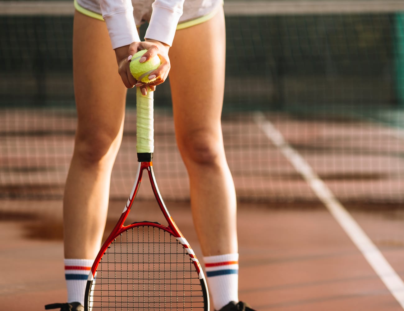 Giocatrice di tennis con racchetta e pallina su un campo in terra rossa